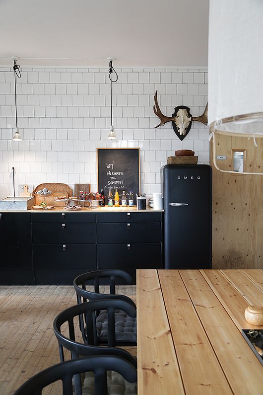 The matte black cabinetry in the kitchen of Swedish cafe Sågverket – möten rum & kök contrasts with the timber benchtop and white subway tiles. Photography courtesy of Sågverket – möten rum & kök.