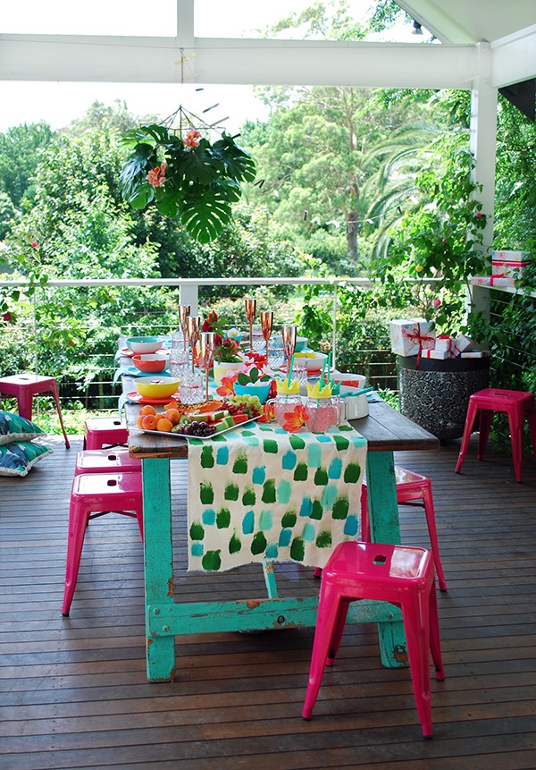 A tropical Christmas table setting - with a handpainted table runner adorned with hibiscus, frangipani and a monstera chandelier. Photo by Lisa Tilse for We Are Scout.