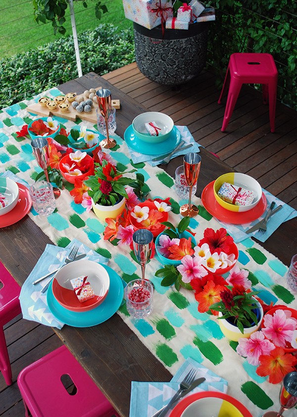 A tropical Christmas table setting - with a handpainted table runner adorned with hibiscus, frangipani and a monstera chandelier. Photo by Lisa Tilse for We Are Scout.