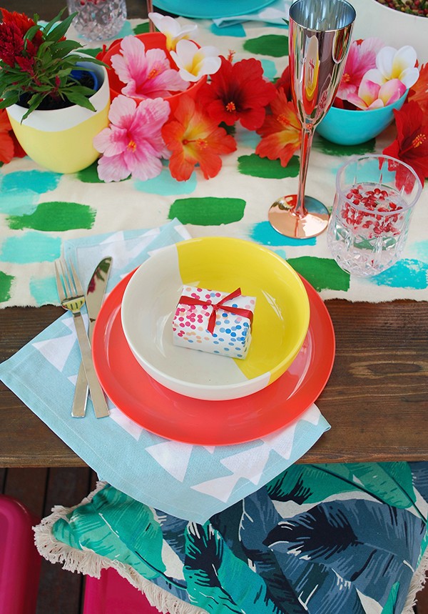 A tropical Christmas table setting - with a handpainted table runner adorned with hibiscus, frangipani and a monstera chandelier. Photo by Lisa Tilse for We Are Scout.