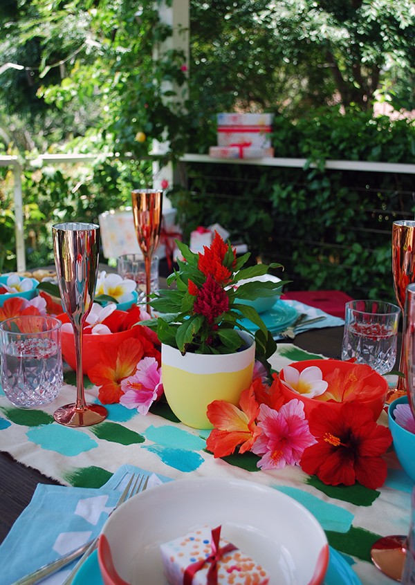 A tropical Christmas table setting - with a handpainted table runner adorned with hibiscus, frangipani and a monstera chandelier. Photo by Lisa Tilse for We Are Scout.