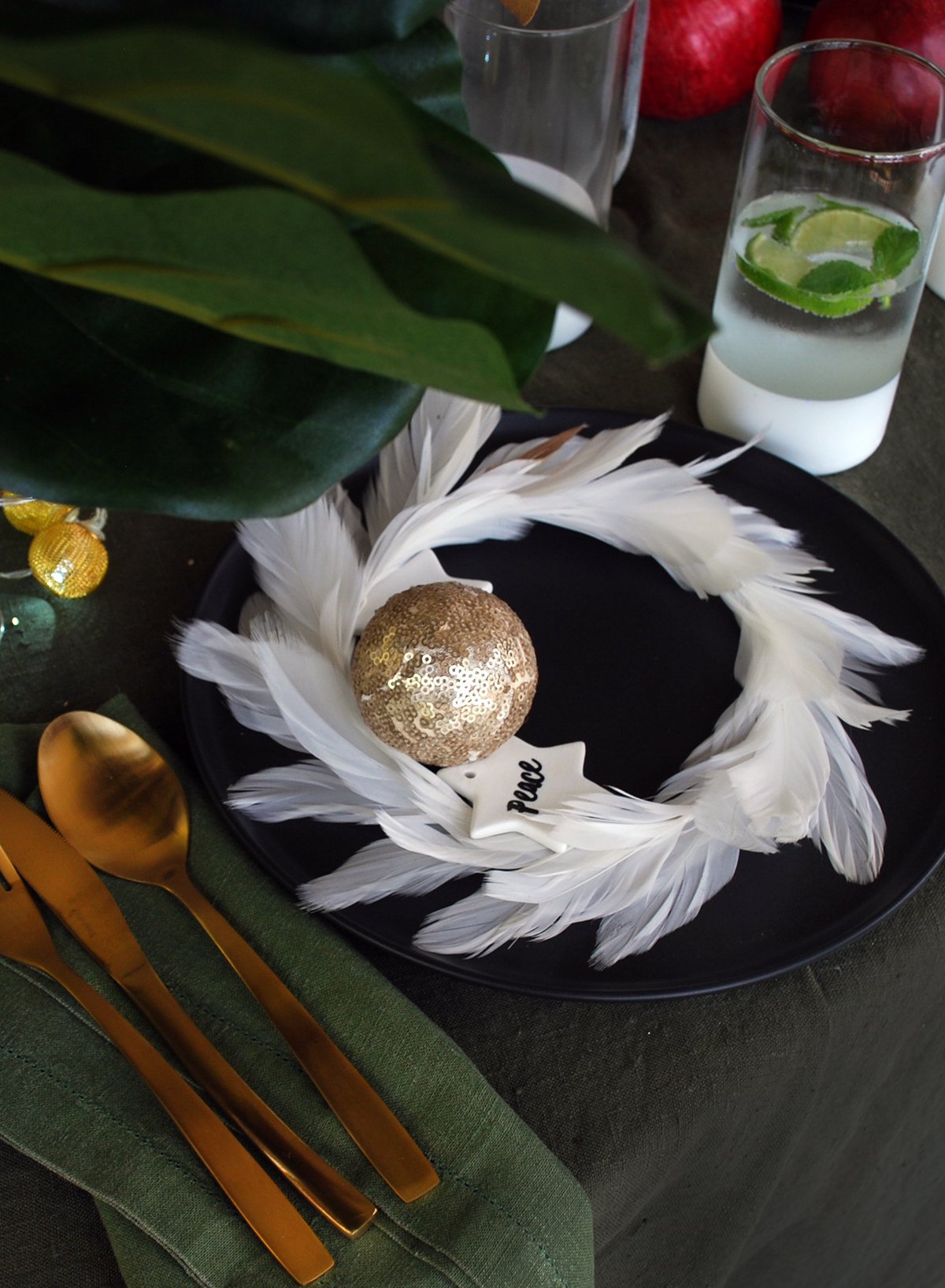 How to style a black Christmas table setting. Add texture and colour with this feather wreath as a place setting.