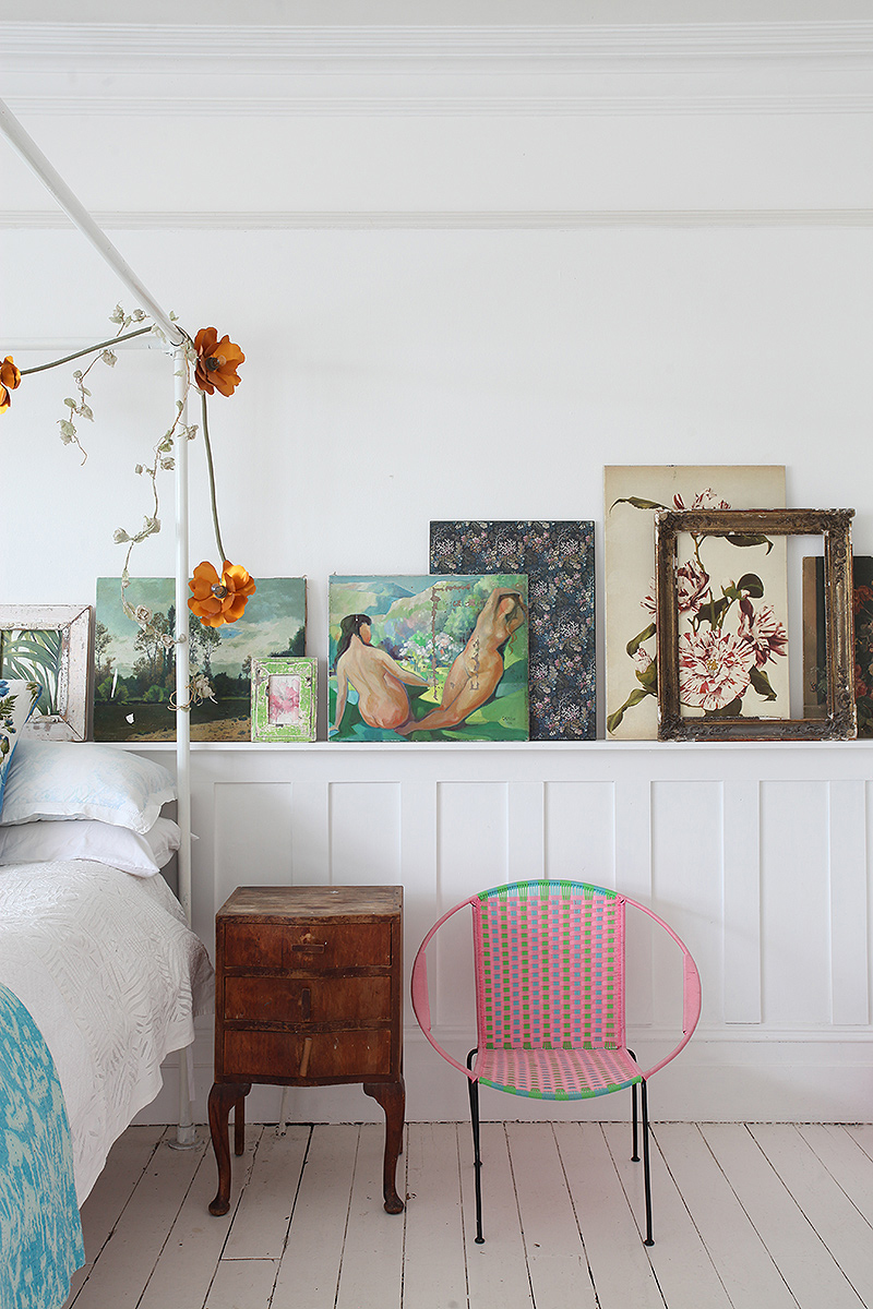 An eclectic collection of paintings adds interest to the bedroom in this modern bohemian home